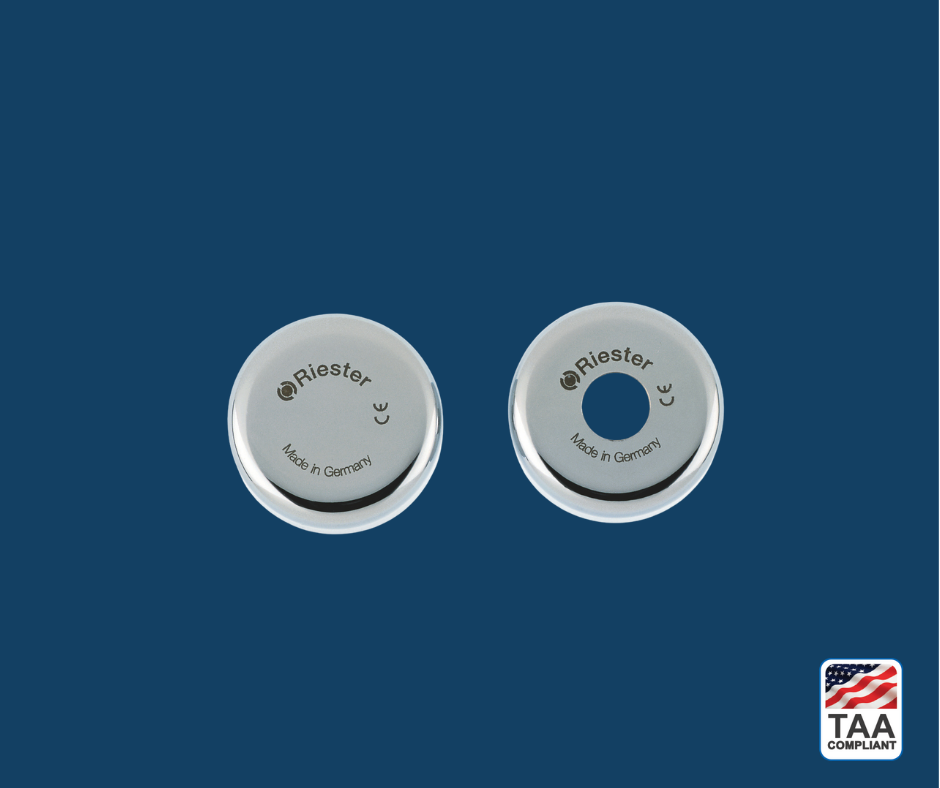 Riester uni econom battery handle cover with matte black body and smooth top cap, positioned centrally on blue background; TAA Compliant box featuring American flag visible in lower right corner.