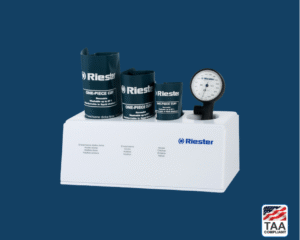 Riester R1 shock-proof analog sphygmomanometer with coiled tubing and gauge placed inside white storage box; TAA Compliant box with American flag in lower right corner