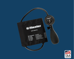 Riester R1 shock-proof analog sphygmomanometer with black bulb and dial face, shown angled to highlight pressure gauge and reinforced casing; positioned centrally on blue background with TAA Compliant box featuring American flag visible in lower right corner.