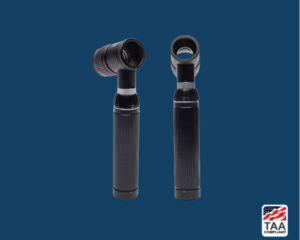 Black dermatology scope with silver accents and rounded viewing head, positioned centrally on blue background; TAA Compliant box featuring American flag visible in lower right corner.