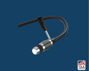 Riester ri-magic LED examination light with matte black body and silver clip attachment, positioned centrally on blue background; TAA Compliant box featuring American flag visible in lower right corner.