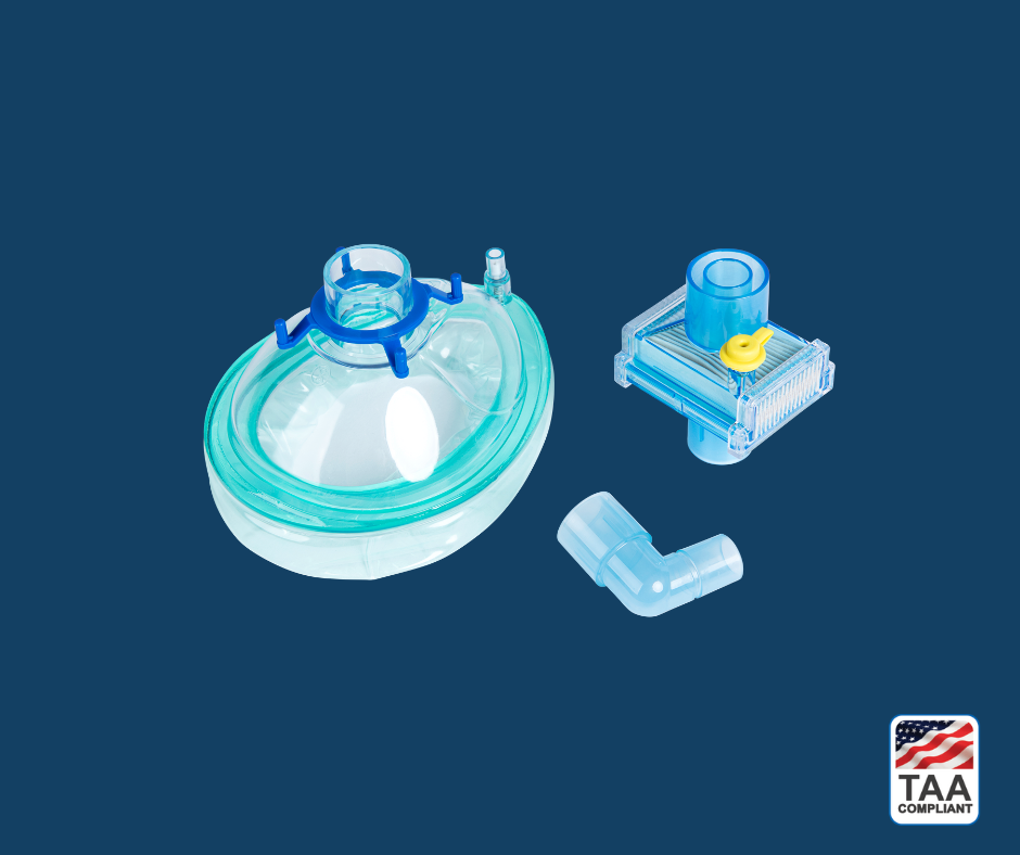 Pall VMPKLA breathing filter with integrated mask interface — shown in angled profile view to highlight translucent housing, dual coaxial port configuration, ribbed filtration chamber, and ergonomic mask connection; positioned centrally on blue background with TAA Compliant box featuring American flag visible in lower right corner.