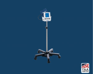 Digital blood pressure monitor with stand placed flat in center of picture with blue background. TAA Compliant symbol with American flag in bottom right-hand corner.